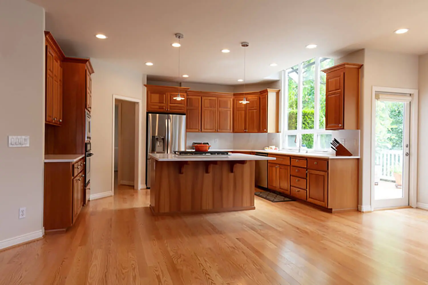 Kitchen cabinet refinishing process shown in a bright kitchen with natural wood cabinets, island, and updated finishes.