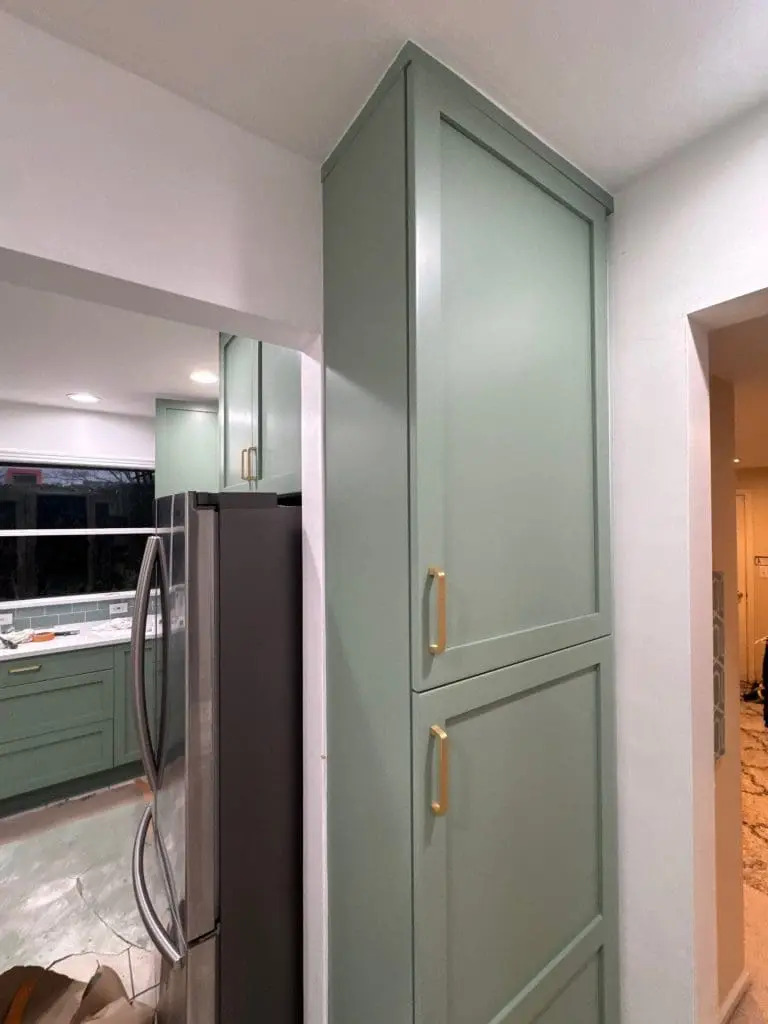 Custom pantry refinishing by Painters in Refined Painting LLC in Seattle, WA featuring eucalyptus green cabinetry and modern gold pulls.