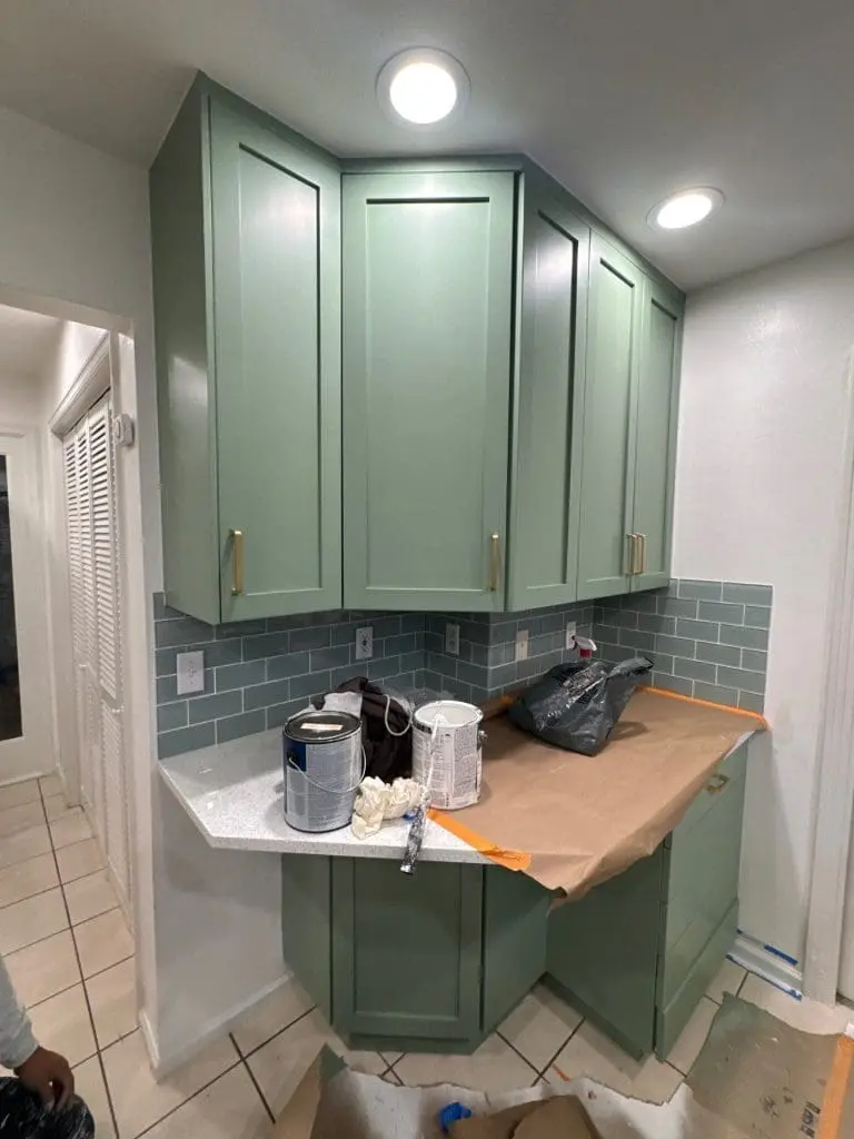 Professional kitchen cabinet transformation by Painters in Refined Painting LLC in Seattle, WA featuring sage green finishes and gold hardware.