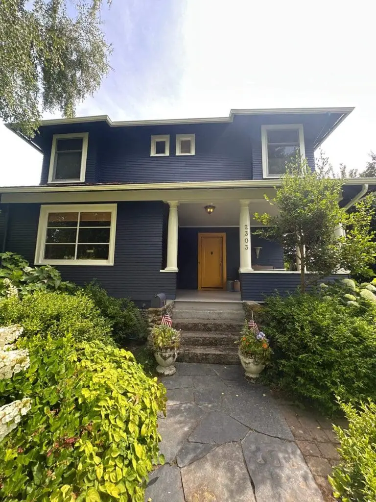 Craftsman home with deep navy siding and a bold yellow door, expertly coated by painters in Refined Painting LLC in Seattle, WA.