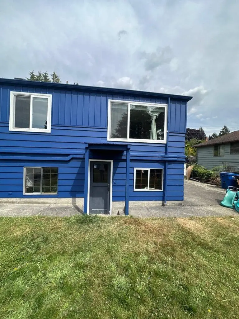 Side profile of a home showcasing a flawless deep blue exterior and crisp white window frames, completed by professional painters in Refined Painting LLC in Seattle, WA.