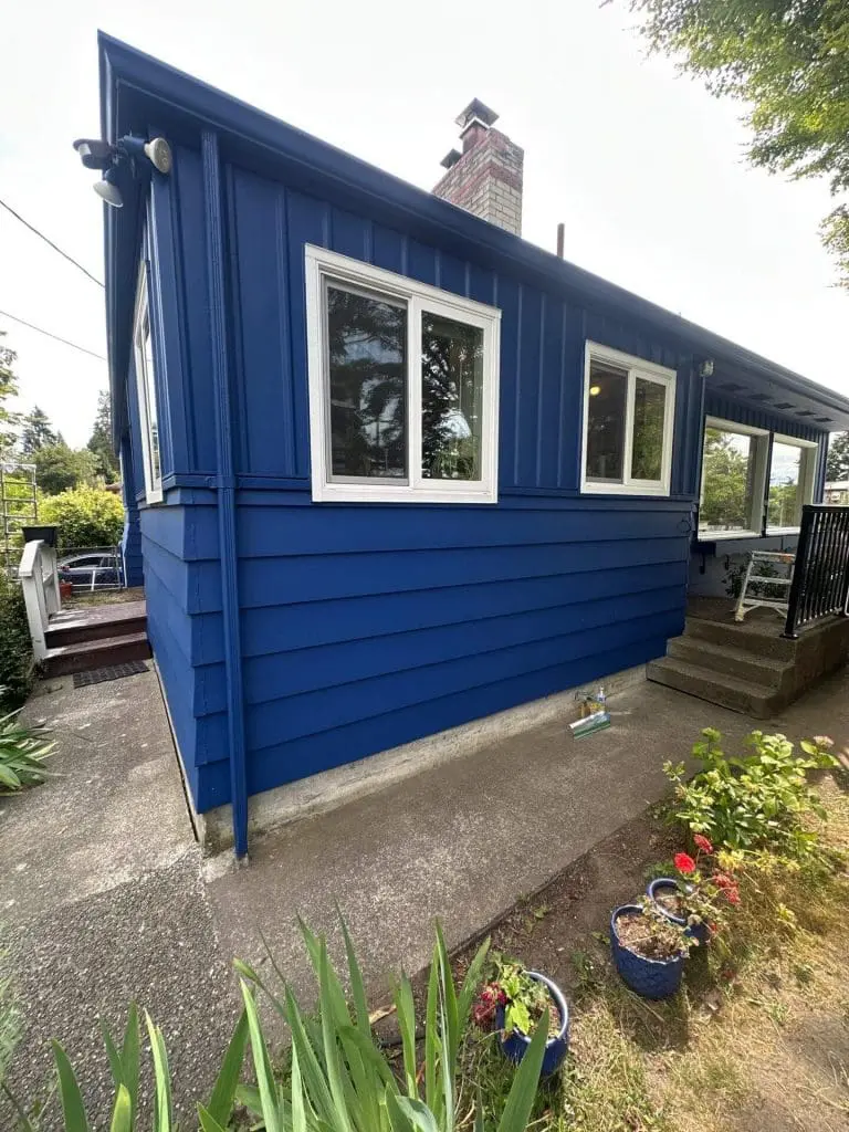 A home featuring vibrant royal blue horizontal and vertical siding with crisp white window trim, showcased by the expert painters in Refined Painting LLC in Seattle, WA.