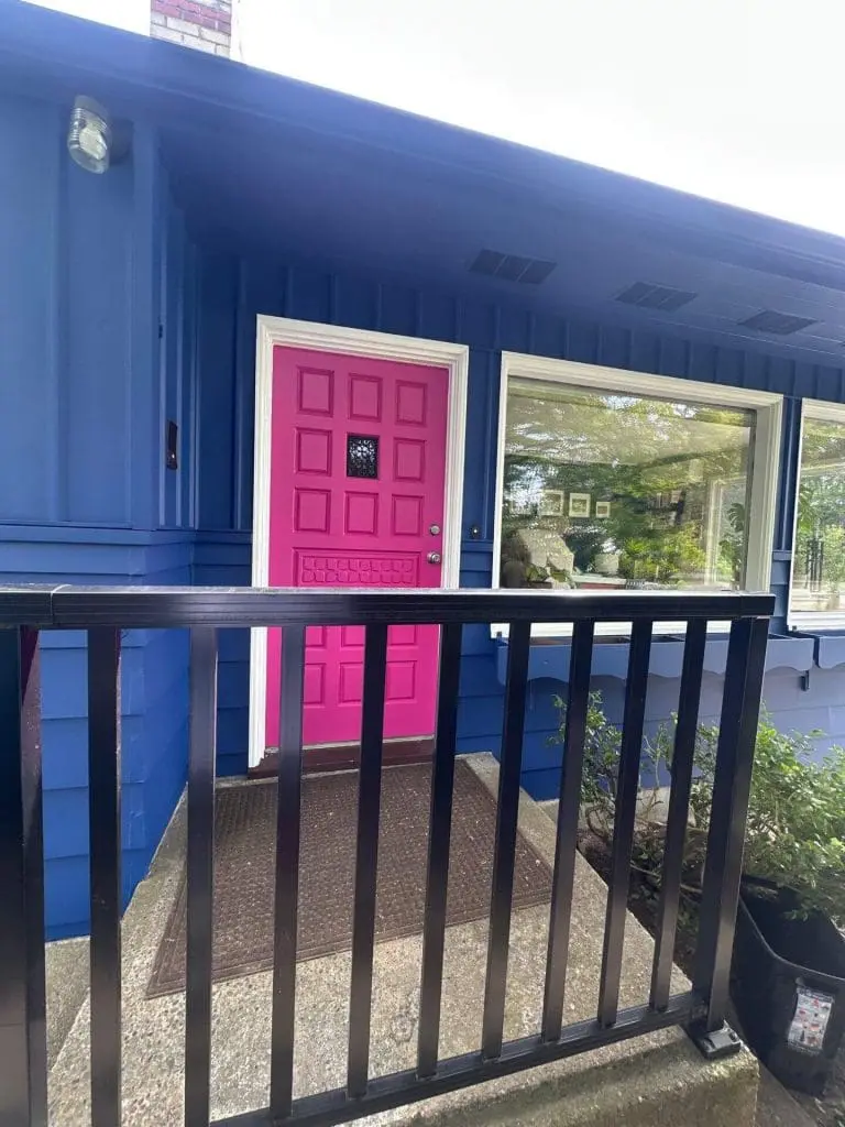 A blue mid-century modern house featuring a vibrant pink front door, expertly finished by the residential painters at Refined Painting LLC in Seattle, WA.