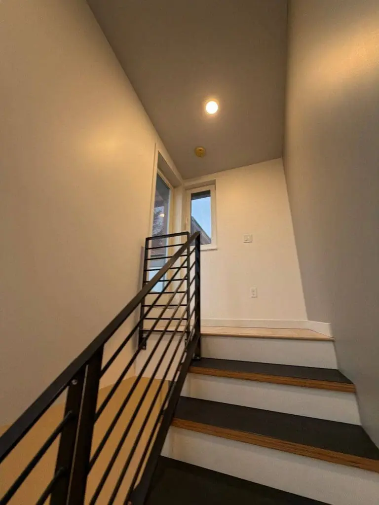Modern interior staircase with clean neutral wall paint and black metal railing, professionally painted by a Seattle painting company in Seattle, WA.