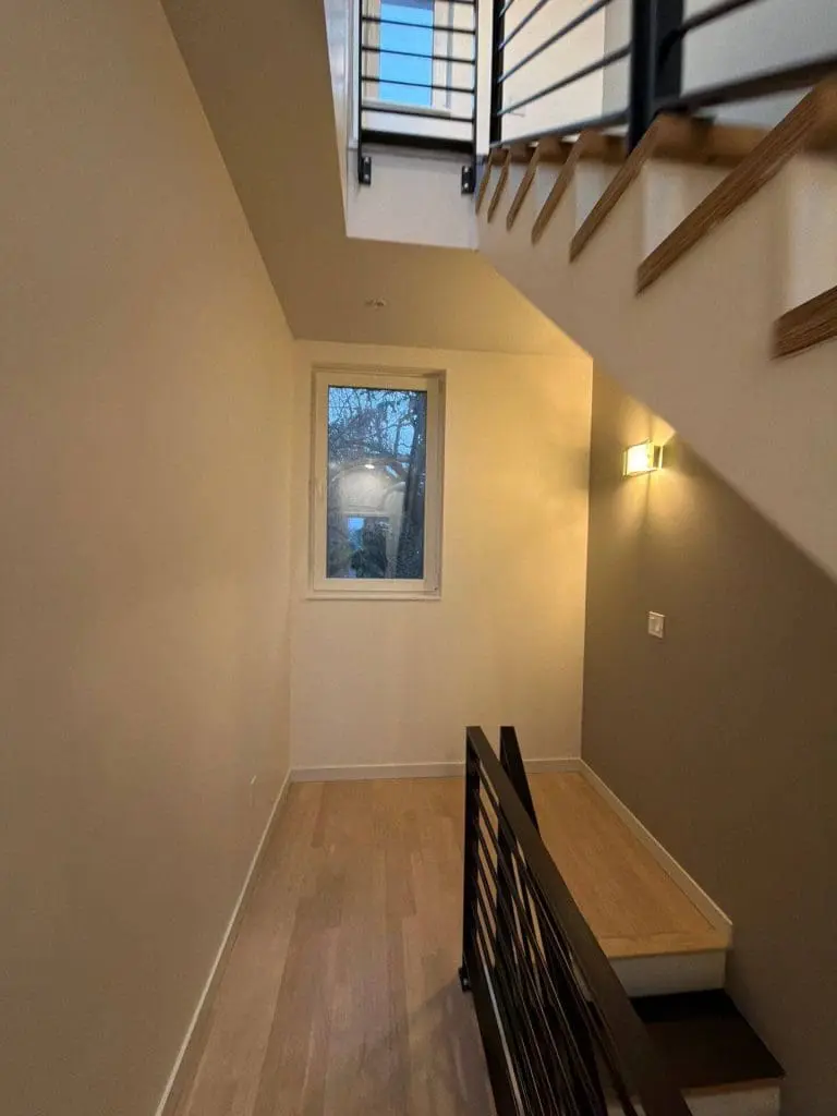 Modern interior staircase with custom wood treads and black metal railing painted by Refined Painting LLC, Seattle, WA