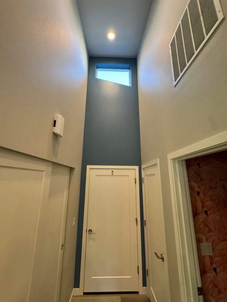 A vaulted hallway featuring a slate blue accent wall and crisp white trim, professionally finished by Painters in Refined Painting LLC in Seattle, WA.